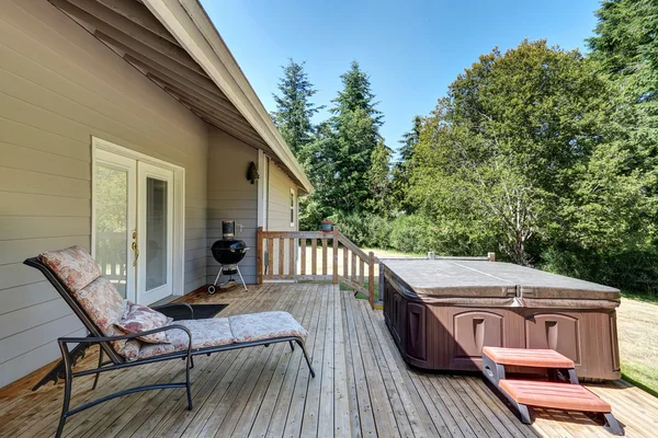 Achtertuin buitenkant van het huis met patio gebied en hot tub op het dek van de staking. — Stockfoto