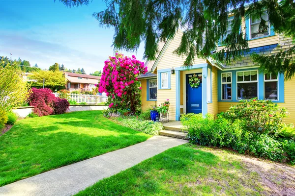 Kleines gelbes Haus außen mit blühendem Rhododendron — Stockfoto