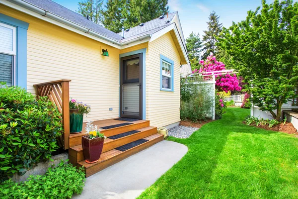 Casa amarilla patio trasero con pequeño porche y escaleras — Foto de Stock