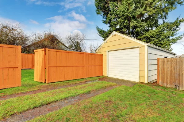 Small beige detached garage at the fenced backyard