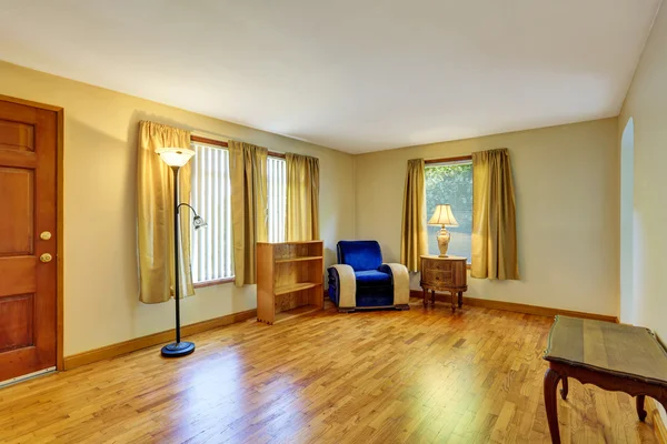 Gezellige zitkamer met hardhouten vloer en blauwe fauteuil in de hoek. — Stockfoto