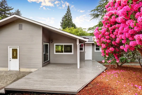 Well kept backyard garden of siding trim house with wooden walkout deck — Stock Photo, Image