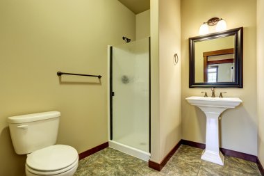 Fayans zemin, lavabo, tuvalet ve cam duş kapısı ile banyo iç.