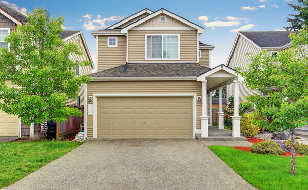 American house exterior with garage, driveway and well kept lawn.