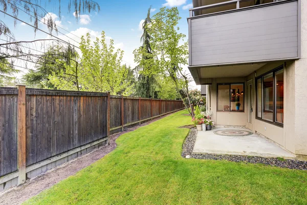 Umzäunter Hinterhof mit gepflegtem Rasen. Betonboden Veranda und Hinterhof. — Stockfoto