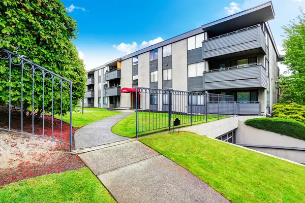 Stor beige bostadshus med tre våningar och balkonger. Välskött gräsmatta — Stockfoto