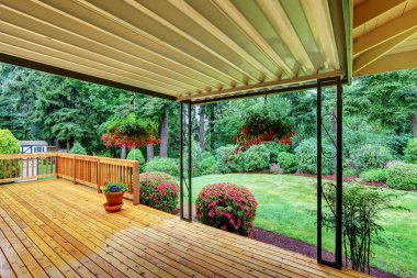 Wooden walkout deck. Well kept garden with bushes and flowers.