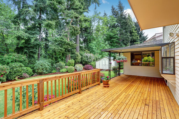 Wooden walkout deck. Well kept garden with bushes and flowers.