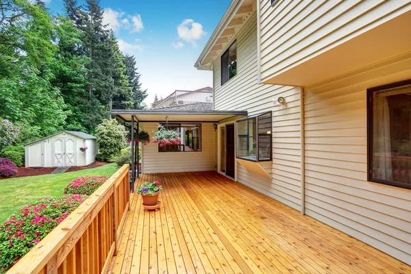 Wooden walkout deck. Well kept garden with bushes and flowers.