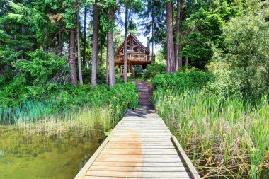 Ahşap döşeme ve büyük balkon ile Ev dış. Ağaçlar etrafında.