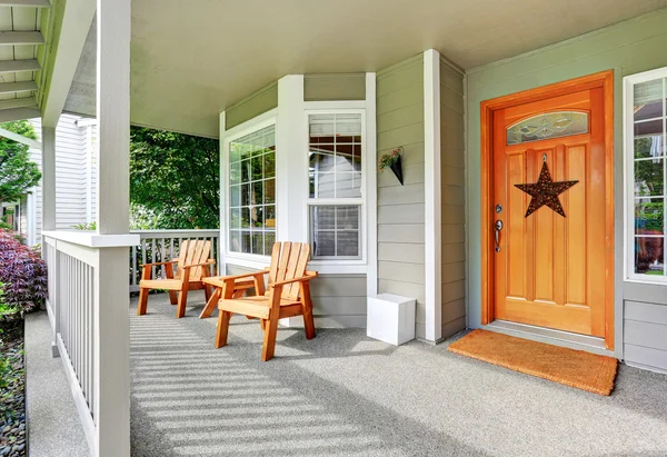 Ruime betonnen veranda met houten stoelen en mooie toegangsdeur. — Stockfoto