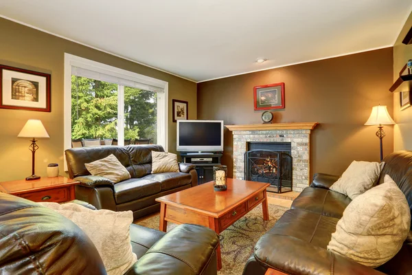 Cozy living room with leather sofas and brick fireplace. — Stock Photo, Image