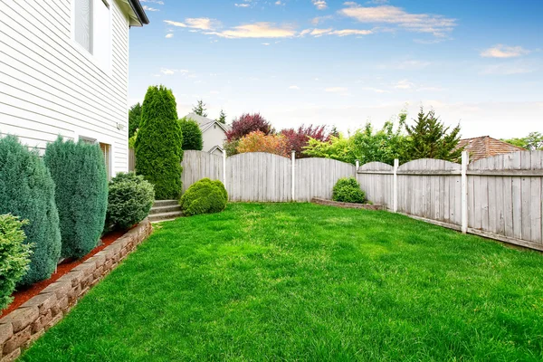 Amplia zona de patio trasero con valla de madera y césped bien cuidado — Foto de Stock