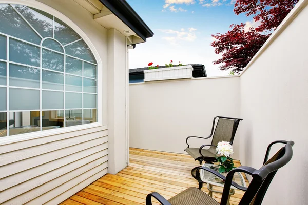 Geschlossener Terrassenbereich mit zwei Stühlen und Holzboden. — Stockfoto