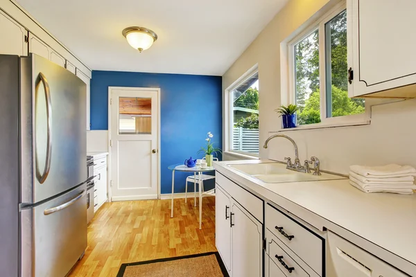 Sala da cucina con armadi bianchi, pareti blu e vetro in grado di — Foto Stock