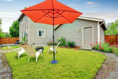 Açık kırmızı şemsiye ile Çitle çevrili arka bahçe veranda, iyi çim tuttu