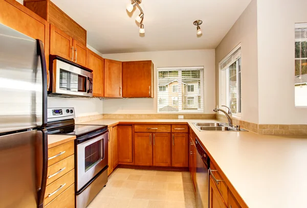 Leere Kücheneinrichtung mit Holzschränken und Fliesenboden. — Stockfoto