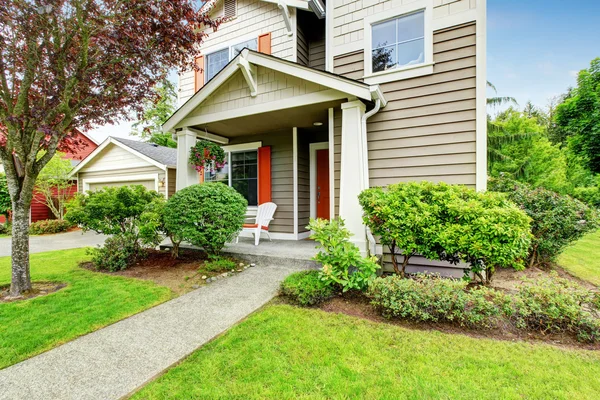 Exterior de la casa con revestimiento, puerta de entrada roja y pasarela de hormigón — Foto de Stock