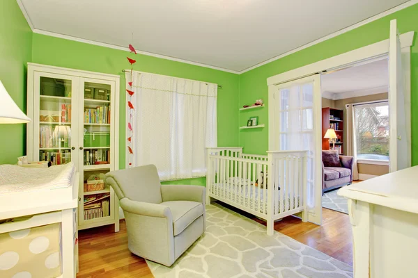 Детская комната в белых и зеленых тонах с бежевым креслом — стоковое фото