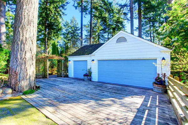 Separate garage with blue door and wooden driveway. — Stock Photo, Image