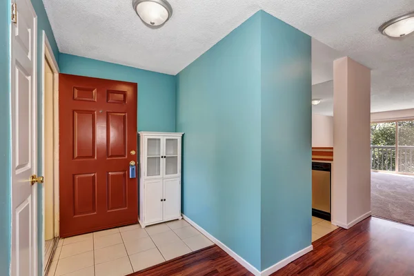 Apartment hallway interior with blue walls, tile and wood flooring.