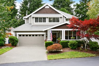 Nice curb appeal of grey house with covered porch and garage clipart