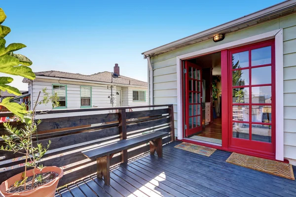 Wooden deck with a bench and red double door — Stock Photo, Image