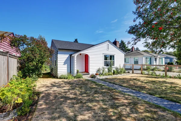 Petite maison blanche avec porte d'entrée rouge . — Photo