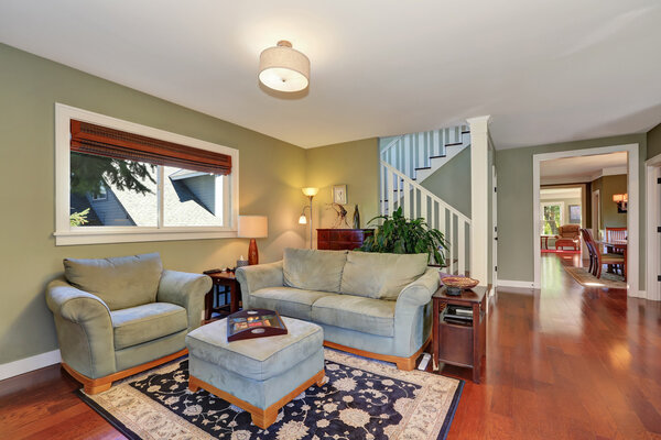 Уютная зона отдыха с легким оливковым диваном и оттоманом
.