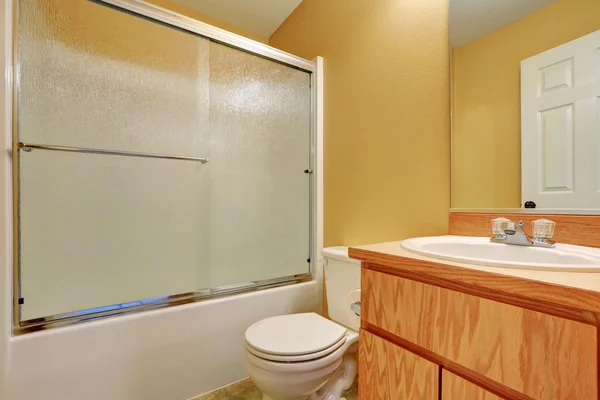 Yellow walls bathroom with glass screened shower bathtub — Stok fotoğraf