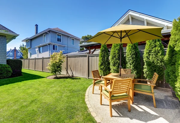 Kleine patio met houten tafelset en paraplu. — Stockfoto