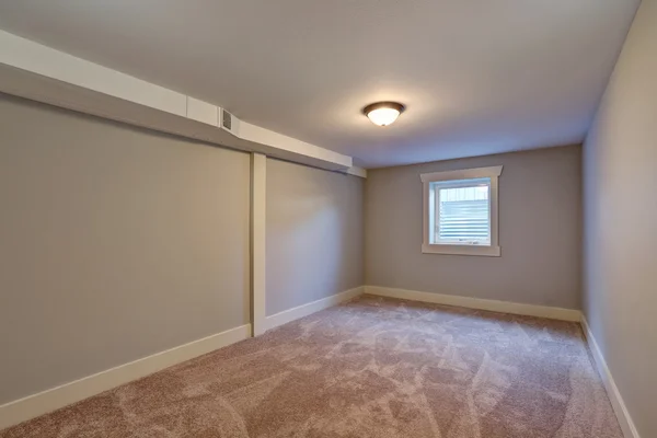 Quarto vazio com piso em carpete bege e pequena janela — Fotografia de Stock
