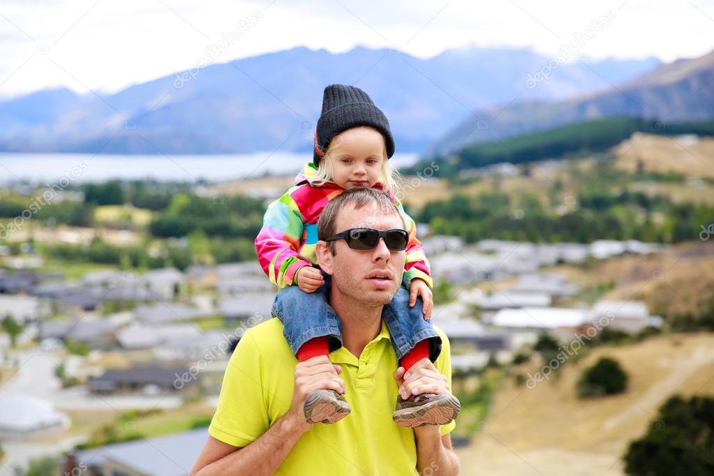 Young man in sunglasses with a little girl on his shoulders. New Zealand
