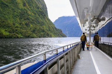 Kızı yla birlikte tur teknesinin güvertesinde yürüyen bir baba. Yeni Zelanda