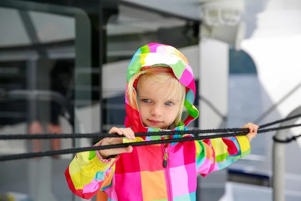 Niño adorable en abrigo colorido mirando el agua desde el barco de turismo —  Fotos de Stock