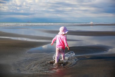 Cute Little girl walking on New Plymouth beach, NZ clipart