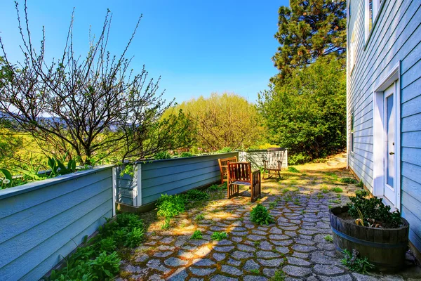 Back yard with stone tile floor, patio area and flower beds — Stock Photo, Image