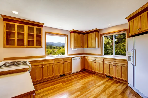 Light brown kitchen cabinets, white appliances and hardwood floor