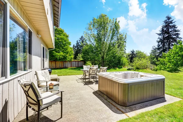 Achtertuin betonvloer patio gebied met hot tub. Goed onderhouden gazon rond. — Stockfoto