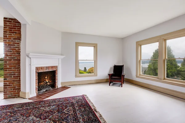 Intérieur de chambre traditionnelle vide dans des tons blancs avec cheminée en brique et tapis — Photo