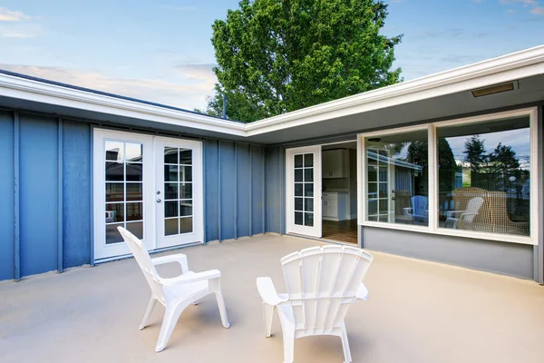 Maison de campagne bleue avec patio au sol en béton avec chaises . — Photo