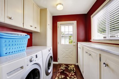 Laundry room interior with white cabinets and red walls. clipart