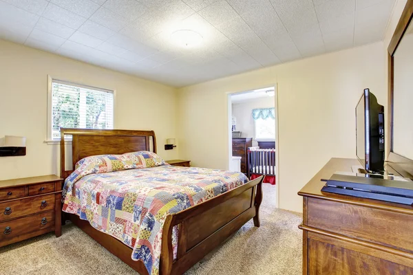 Interior del dormitorio amueblado de madera con ropa de cama agradable y televisor —  Fotos de Stock