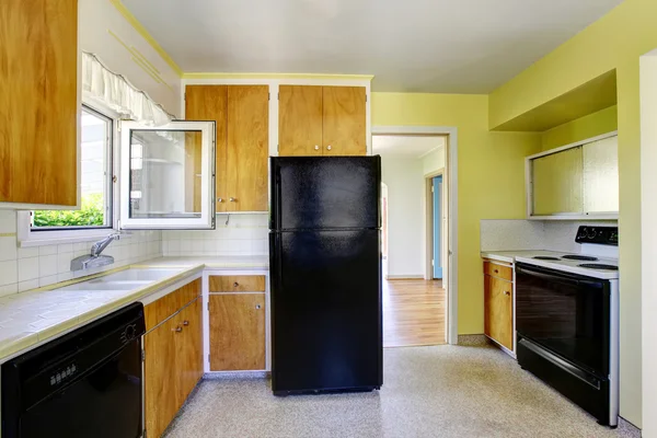 Pequeño interior de la cocina con paredes amarillas, gabinetes de madera y encimera de azulejos . — Foto de Stock