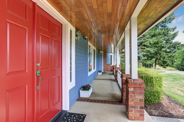 Blue house backyard with concrete floor patio area and well kept garden.