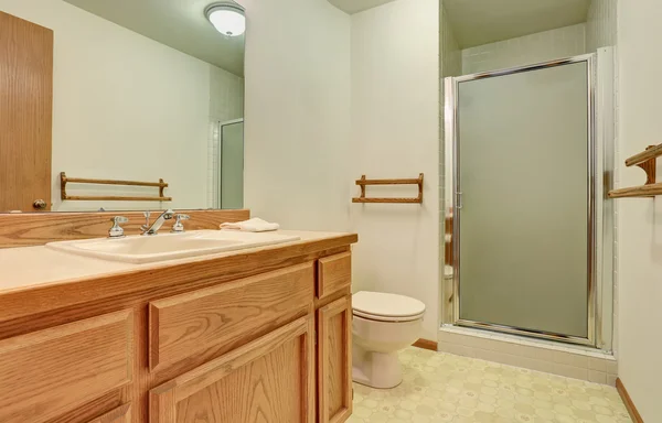Интерьер ванной комнаты с деревянным шкафом, большим зеркалом и кафельным полом . — стоковое фото
