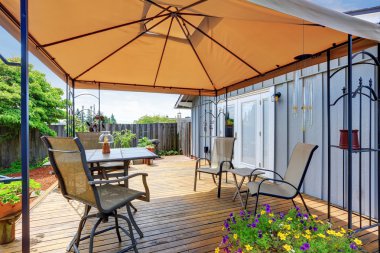 Masa seti ve açık turuncu şemsiye ile Arka bahçe veranda alanı