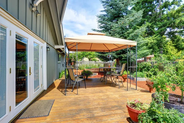 Backyard patio area with table set and opened orange umbrella — Stock Photo, Image