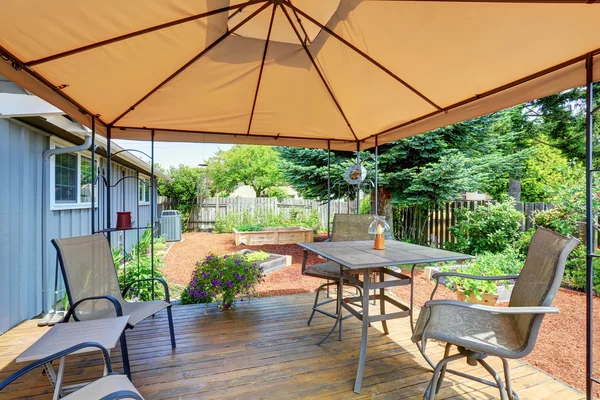 Задний дворик с набором стола и открытым оранжевым зонтиком — стоковое фото