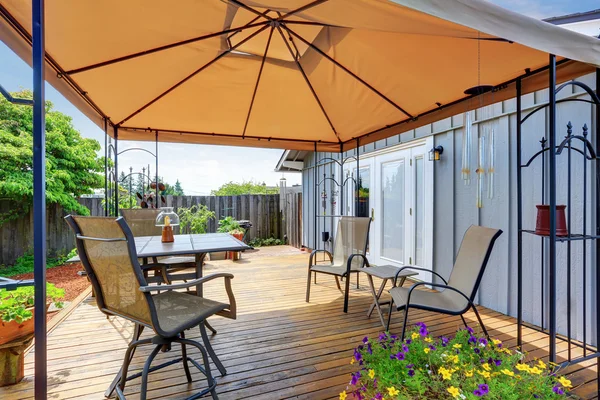 Podwórko patio z zestawem stołów i otwartym pomarańczowym parasolem — Zdjęcie stockowe